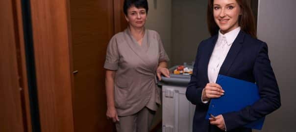 Hotel manager and cleaning lady posing for camera after room inspection