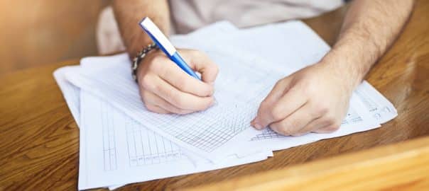 Hands, man and writing with documents at cafe for finance planning, vendor contract and inventory budget. Person, paperwork and pen with feedback form, sales profit and invoice information for growth