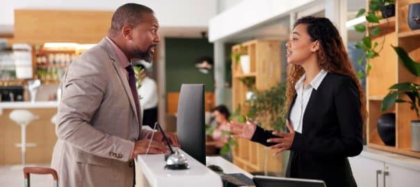 Angry, client and woman in hotel, receptionist and upset with hospitality, displeased or unhappy. People, employee or guest at counter, customer service or luxury with stress, dissatisfy or concierge.