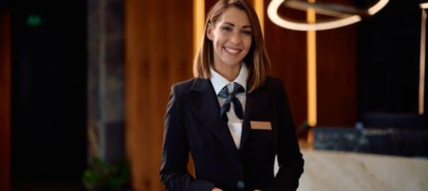 Happy female concierge in hotel hallway looking at camera. Copy space.