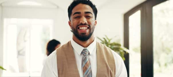 Hospitality, portrait and man at hotel reception for customer service, welcome or luxury accommodation. Smile, friendly concierge and happy in lobby for check in assistance, help or travel booking
