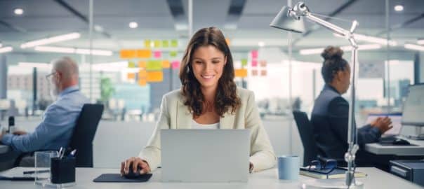 Woman smiling while looking at laptop computer in her work office.
