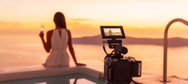 Video camera filming actress woman acting for movie on luxury hotel location behind the scenes of shoot. Professional videography equipment shooting outdoor.