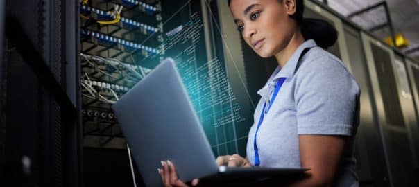 Laptop, network and data center with a black woman it support engineer working in a dark server room. Computer, cybersecurity and analytics with a female programmer problem solving or troubleshooting.