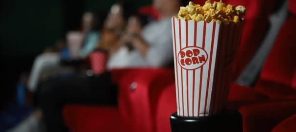 Pop corn and happy people in cinema enjoying a movie, popcorns and beverages over the weekend.