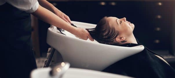 Woman, salon and hair in basin washing, client and eyes closed or applying treatment with person hands. Professional, hairdresser and haircare with customer, pamper and relaxing service with stylist.
