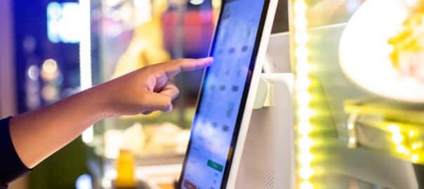 Selective focus to customer's hand is touching a touch screen to order food and pay electronically.