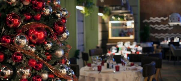 Christmas, New Year red restaurant interior with decorated fur-tree, tables and chairs.