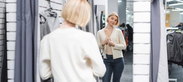 Blurred woman looking at mirror in dressing room in second hand.