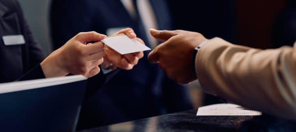 Close up of hotel receptionist giving room cardkey to African American hotel guest.