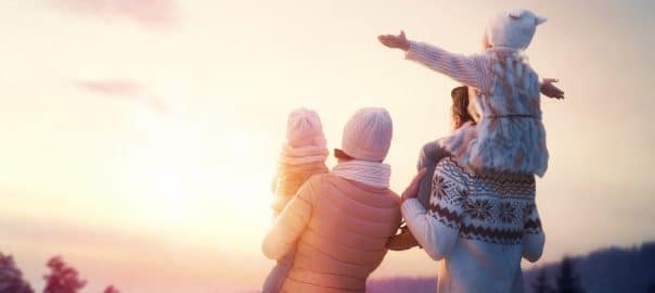 Happy family at sunset. Father, mother and two children daughters are having fun and playing on snowy winter walk in nature. The child sits on the shoulders of his father. Frost winter season.