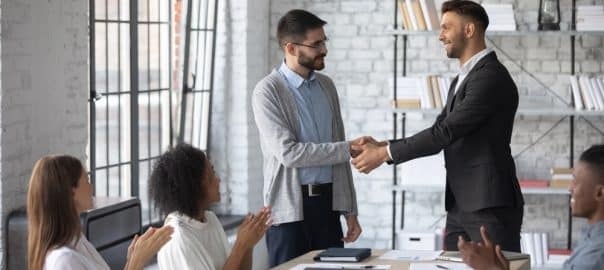 Young Caucasian boss shake hand of male employee, congratulate with job promotion at meeting, confident businessman handshake worker, greeting with employment, get acquainted at team briefing.