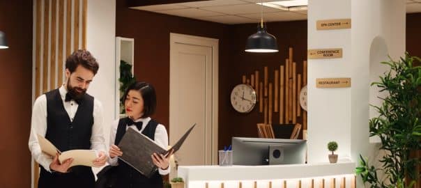 Concierge manager cross referencing tourists booking appointment data at hotel reception desk. Empathetic leadership in a professional resort staff working at check in counter in stylish holiday destination.