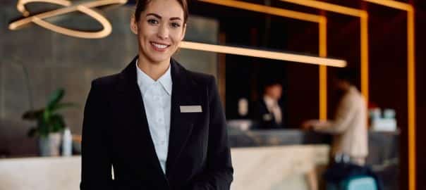Smiling female hotel receptionist in a hallway looking at camera.