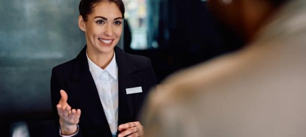Happy female concierge serving a guest at the hotel.