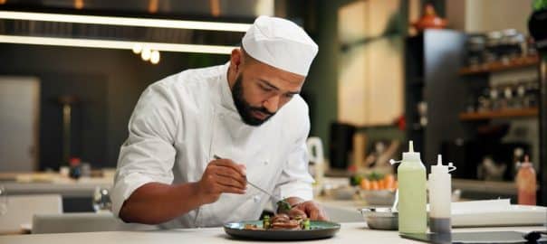 Man, chef and serious with food in kitchen at restaurant for fine dining, meal and creativity. Male employee, professional and cooker with pride for culinarily, hospitality and catering service.