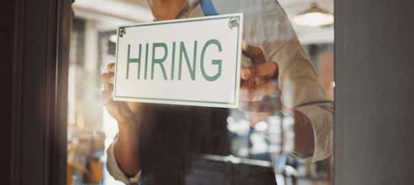 Man, window and business owner with hiring sign for cafe recruitment, job vacancy and hospitality industry. Male waiter, billboard and onboarding invitation, contact us and information of opportunity.
