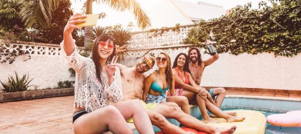 Group of happy friends making pool party taking selfie with mobile smartphone - Young people having fun in exclusive summer tropical vacation - Friendship, tech, holidays and youth lifestyle concept.
