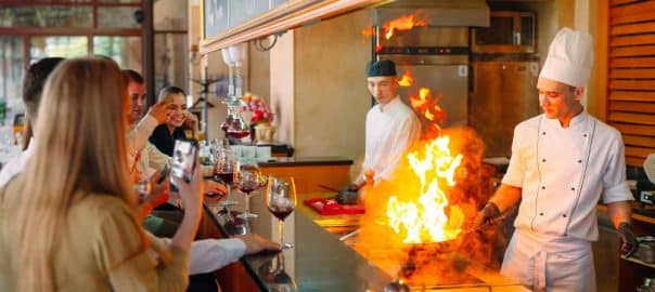 The chef prepares food in front of the visitors in the restaurant.