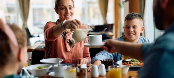 Happy woman and her family enjoying in breakfast while staying at the hotel.