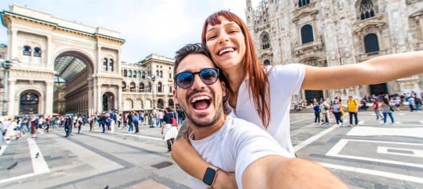 Happy couple taking selfie in front of Duomo cathedral in Milan, Lombardia - Two tourists having fun on romantic summer vacation in Italy - Holidays and traveling lifestyle concept