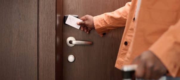 Close up of guest opening hotel room door and pressing keycard to NFC security lock system copy space.