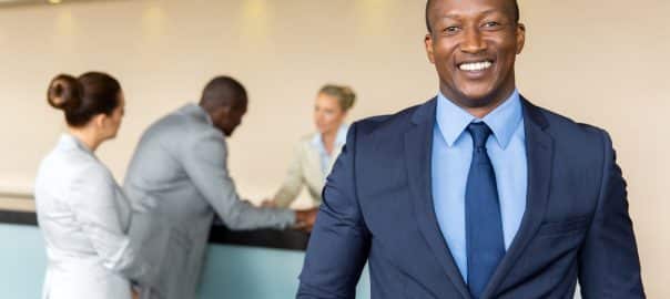 Diversity concept: portrait of happy Black businessman standing at hotel reception.
