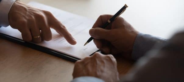 Hands of lawyer pointing at paper for businessman signing contract. Solicitor, legal advisor helping mature client to fill up document, medical insurance form, will, affixing signature. Paperwork.