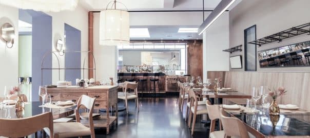 A beautifully designed restaurant interior showcasing a modern and elegant dining area. The space features contemporary furniture, including wooden chairs and tables set with glassware, plates.