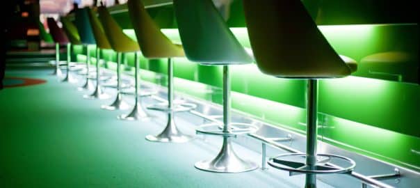 Chairs in row in bar with green lights.