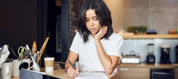 Unhappy female cafe manager singing documents contract standing behind the counter.