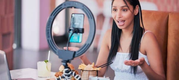 Woman influencer, food review blog and content creator filming online video in cafe restaurant. Creative live streaming, shooting 5g web vlog and virtual mobile phone app broadcast for social media.