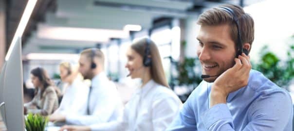 Portrait of call center worker accompanied by his team. Smiling customer support operator at work
