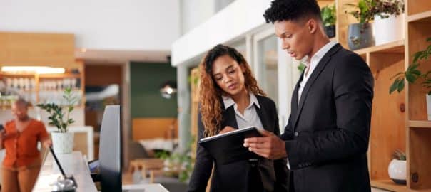 Reception, employees and tablet with teamwork, hotel and accommodation with cooperation. Coworkers, hospitality and service with tech, internet and digital app for schedule and reservation for lodge.