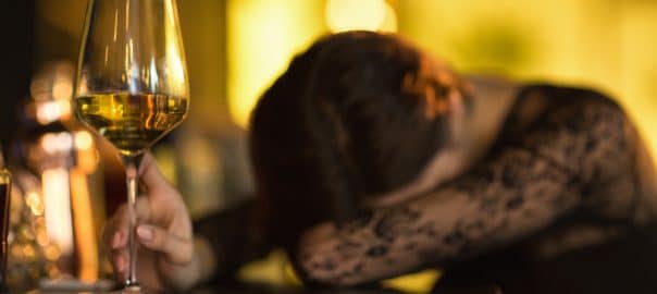 Wasted woman sleeping on the bar counter after drinking too much alcohol selective focus on a glass of wine copyspace booze alcoholic problem addicted addiction lifestyle party event depression.