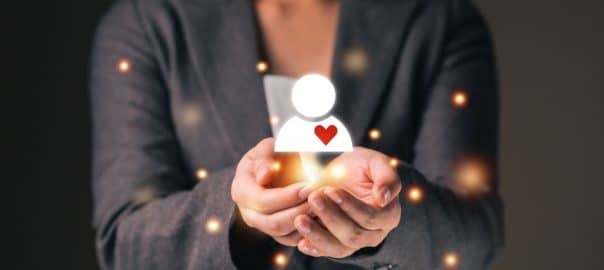 Empathy female manager holding human icon with heart shape over palm hands. Power of emotional intelligent, soft skill development concept.