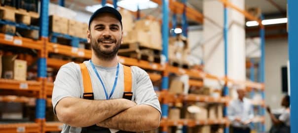 Portrait of happy confident worker at distribution warehouse looking at camera.
