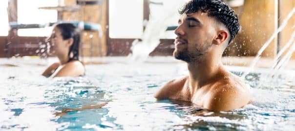 A young couple enjoy themselves in a wellness center. The young people are in a pool at a spa relaxing with pressurized water. Concept of couples between 20 and 30 years old in a spa.