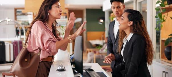 Frustrated, receptionist and people at front desk of hotel for angry client, lost luggage and check in problem. Customer service, concierge and late booking with woman in lobby for appointment error.