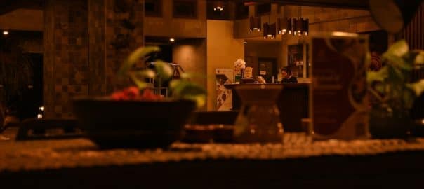 A hotel receptionist working behind the counter at night, with warm lighting and decorative foreground elements. ambient interior captures a peaceful setting.Banyuwangi,Indonesia-2Apr2025