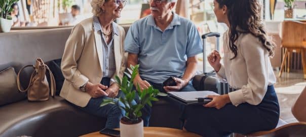 A hotel or travel agency representative is talking with a senior tourist couple offering various tourist services.