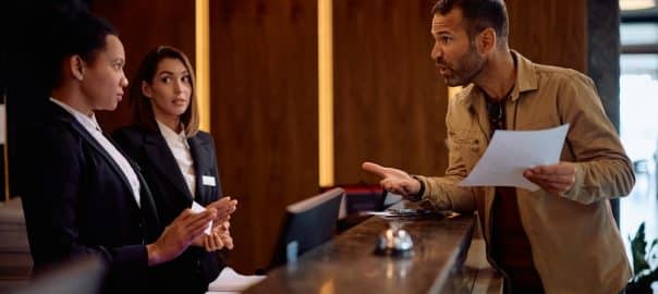 Angry guest discussing with managers while complaining about the bill after a hotel stay.