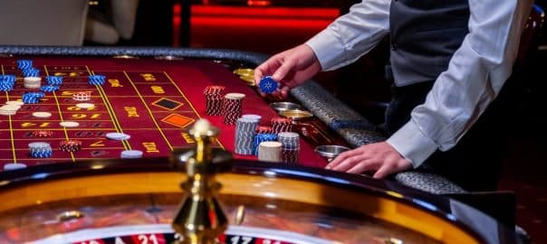 Croupier behind gambling table in a casino. Roulette wheel and croupier hand. A player in a casino, a lot of chips. Money and chips. A screensaver for a casino.