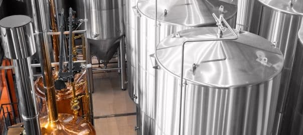 Industrial brewery with large stainless steel fermentation tanks, craft drink.