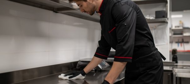 Chef cleaning kitchen counter after cooking in restaurant.