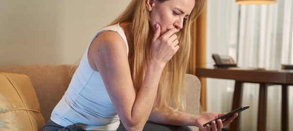 Anxious lady staring at smartphone screen in hotel room